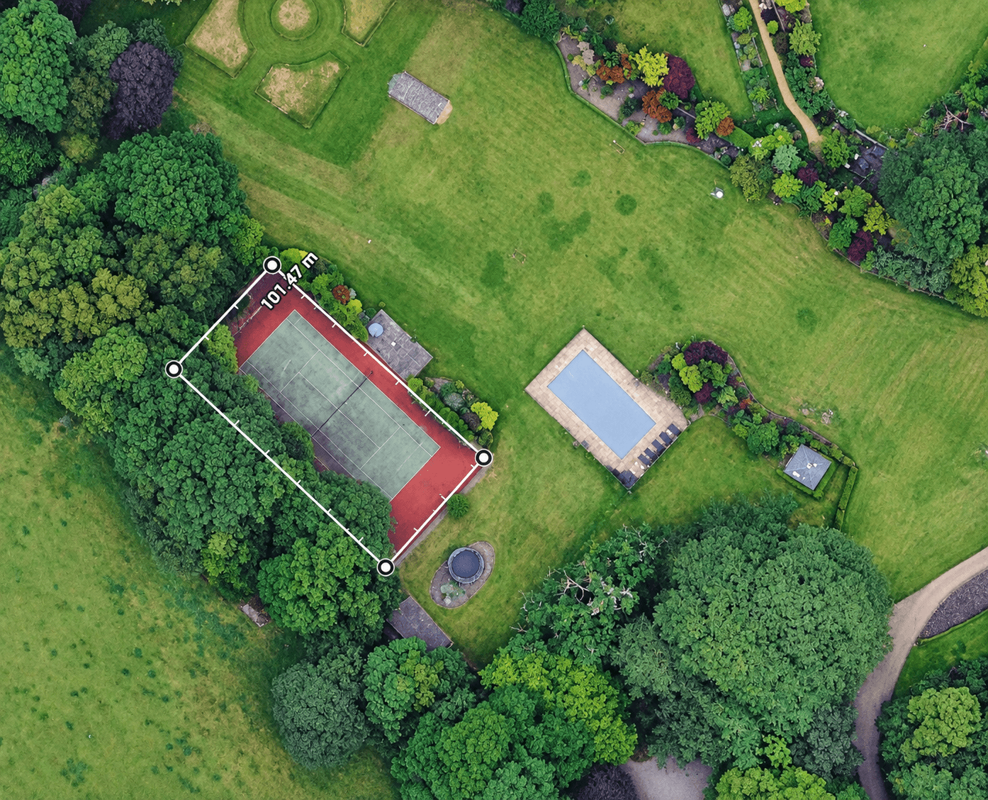 Aerial view of a tennis court with a measured boundary showing a total area of 553.89 square metres.